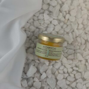 Bottle of Nurishing Bees Wax Creme by Botanistas, on the beach.