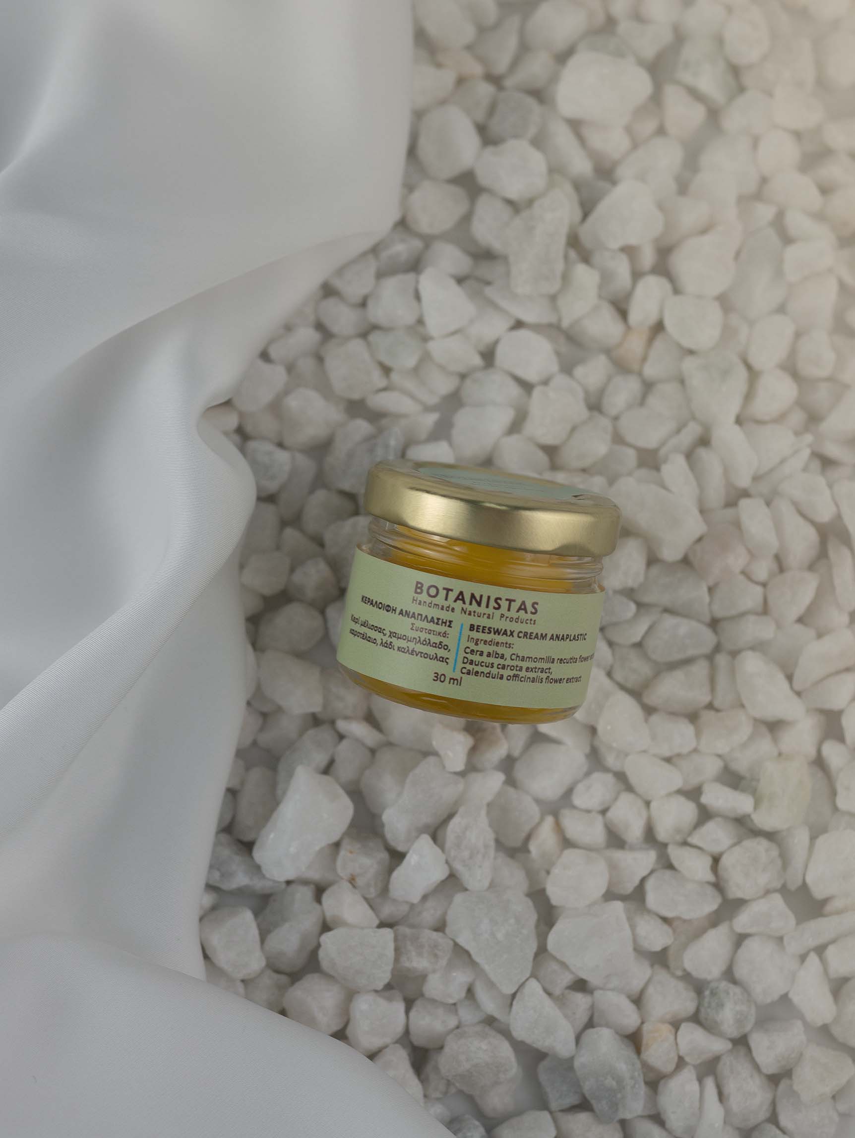 Bottle of Nurishing Bees Wax Creme by Botanistas, on the beach.